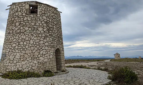 Old stone windmills on Agios Ioannis Beach